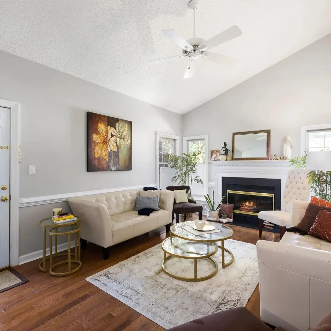 Occupied living room staged with cream sofa, gold coffee table, fireplace and layered neutral decor